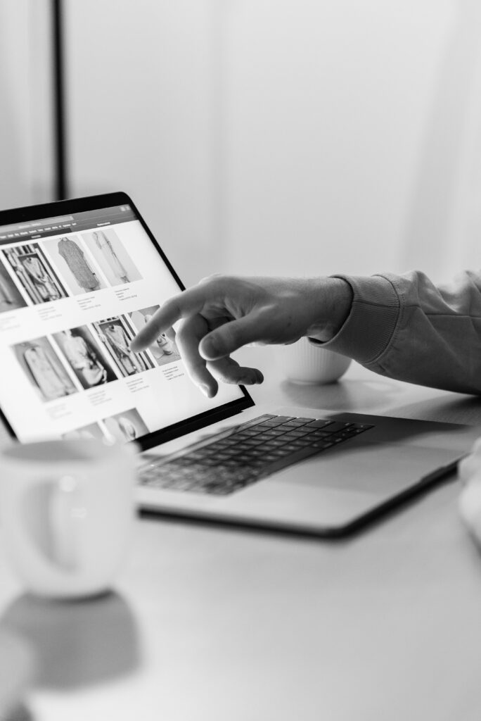 Black and white photo of a person shopping online on a laptop, highlighting e-commerce technology.
